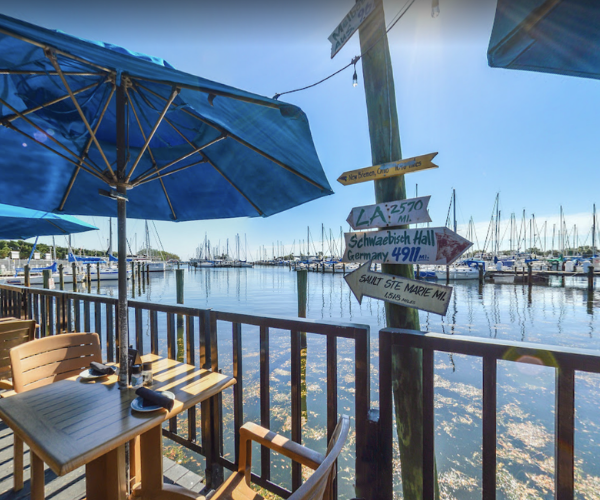 Fresco's Waterfront Bistro view of marina with boats on outdoor patio. Dock post with direction arrows to several distance locations in the USA