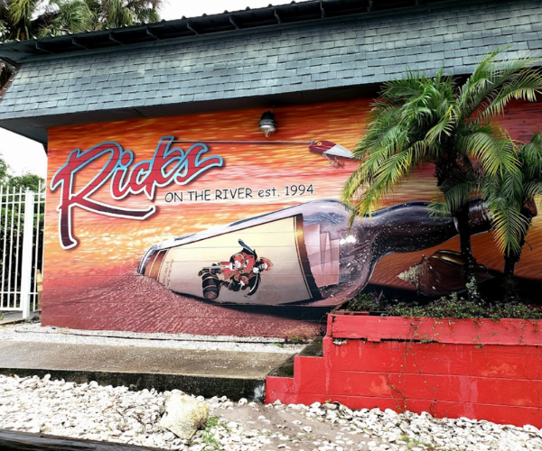 Rick's on the River exterior painted wall with bottle washed up on shore with note inside 